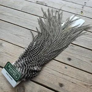 Feather decorative item on a wooden surface with a brand label.