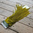 Green feather duster on a wooden surface with a brand tag.